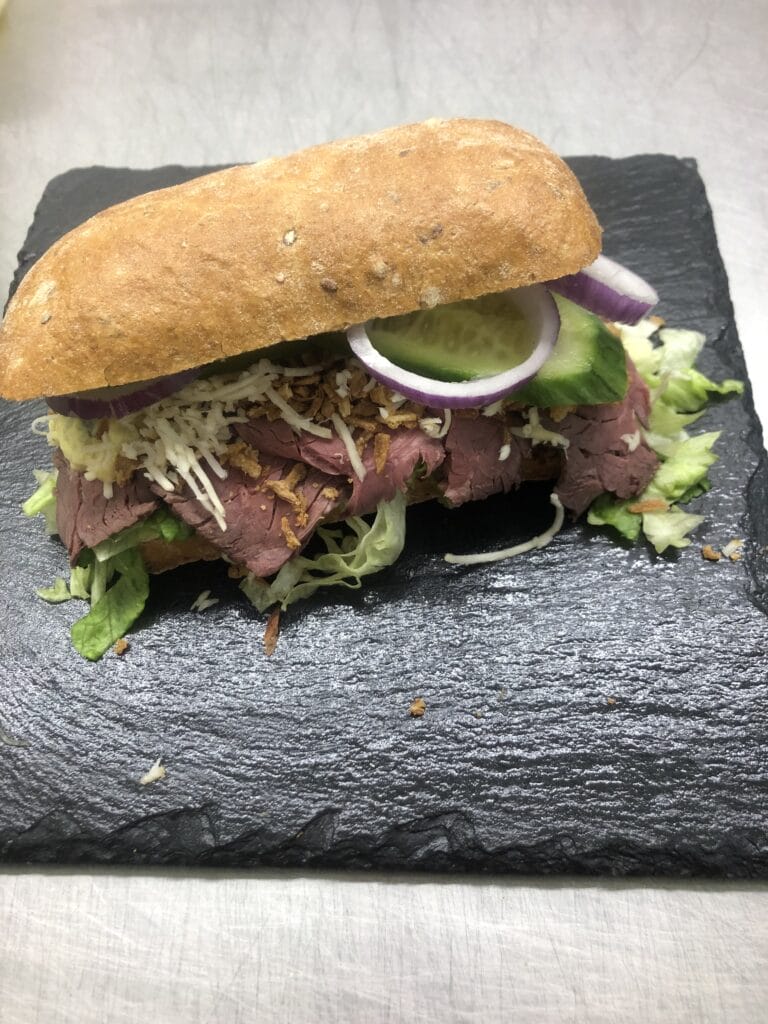 Sandwich med roastbeef, salat og løg på skiferplade