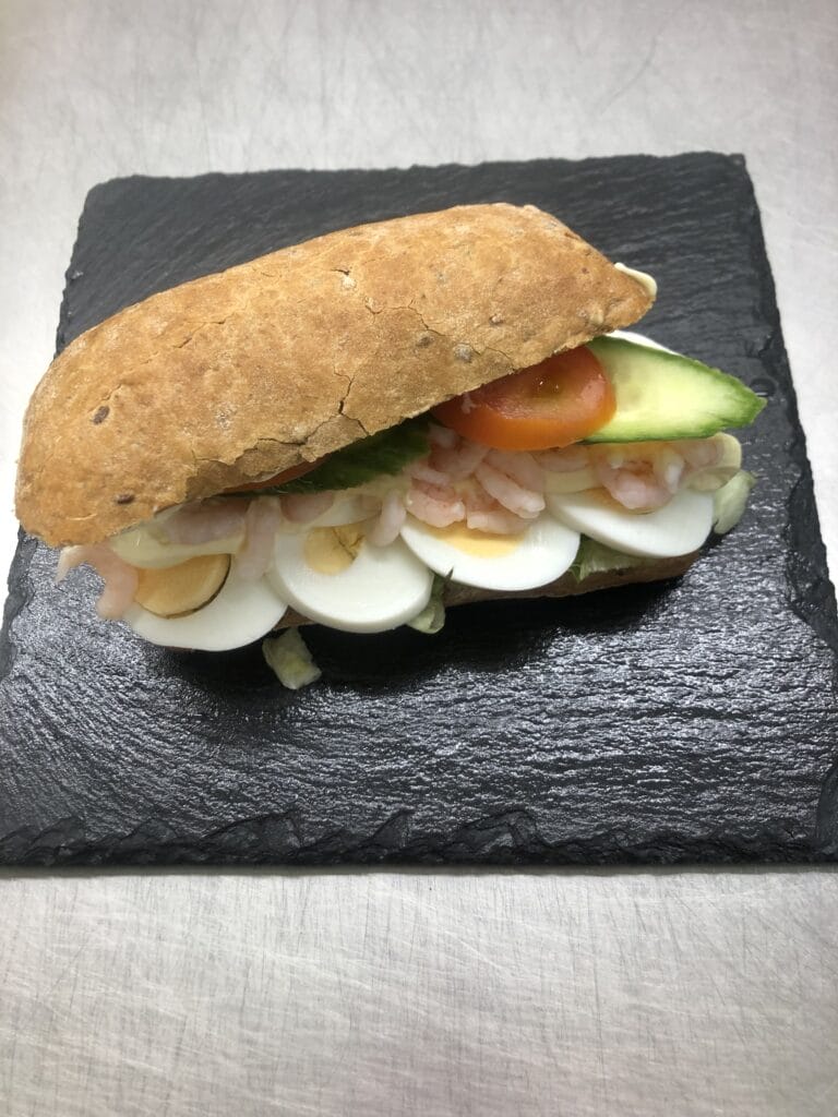 Sandwich med æg, rejer og grøntsager på skiferplade