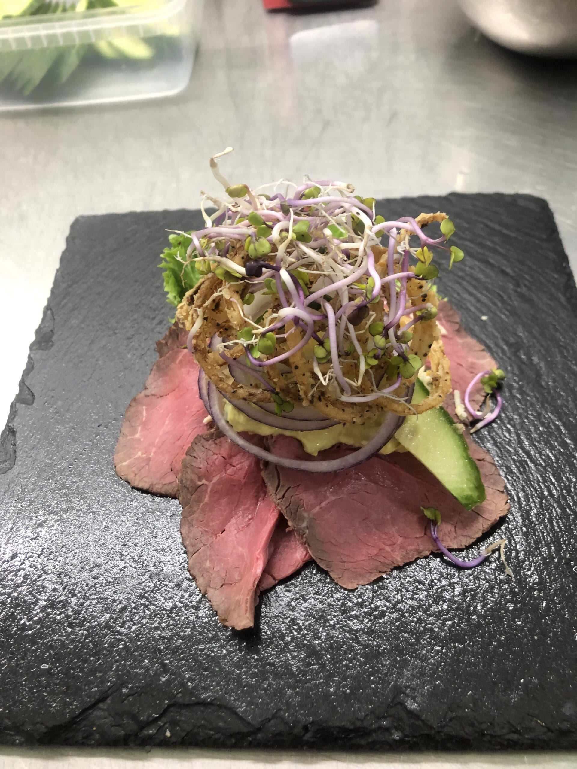 Smørrebrød med roastbeef, løg og spirer på skiferplade