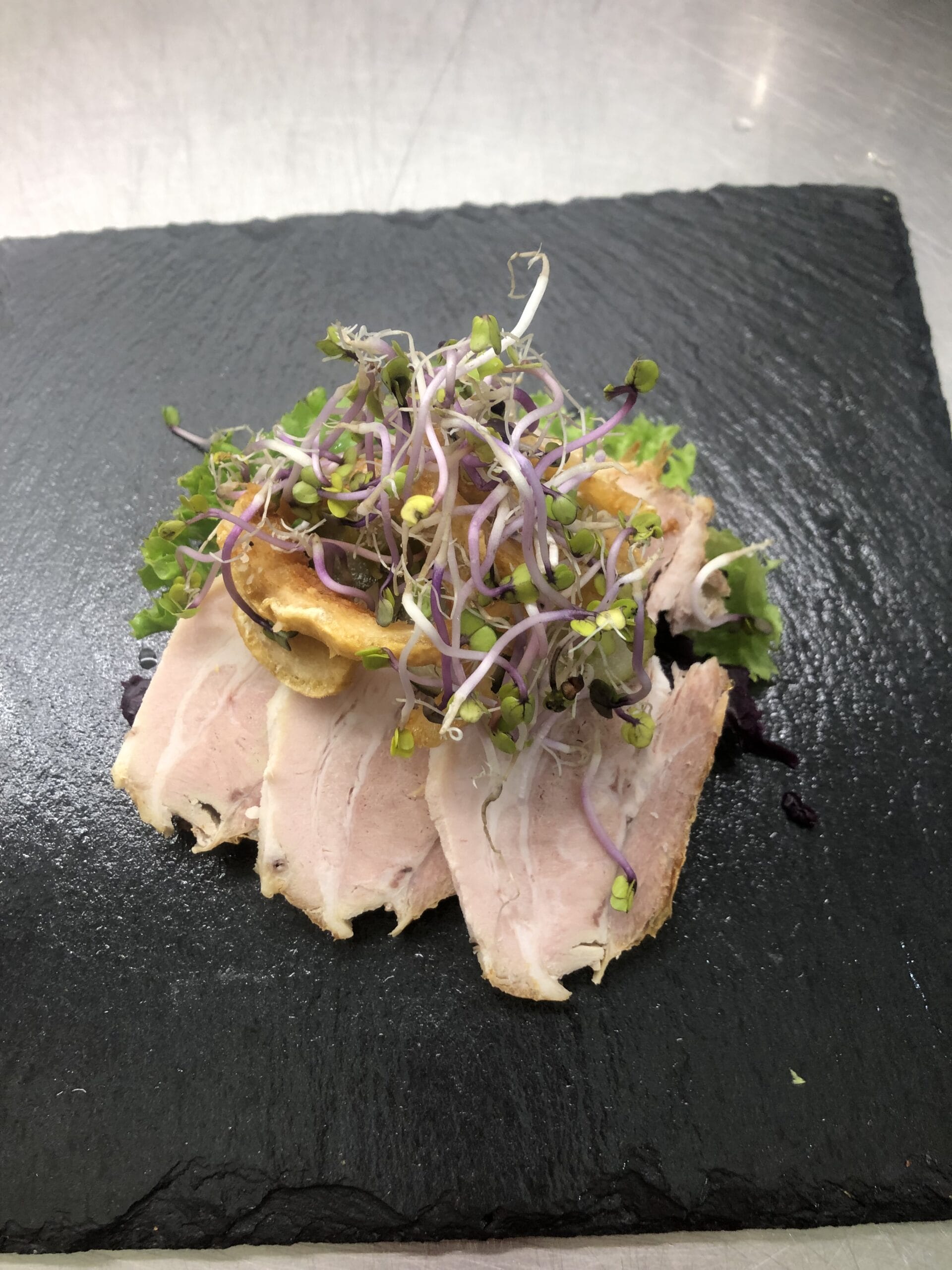 Flæskesteg med spirer på sort skiferplade